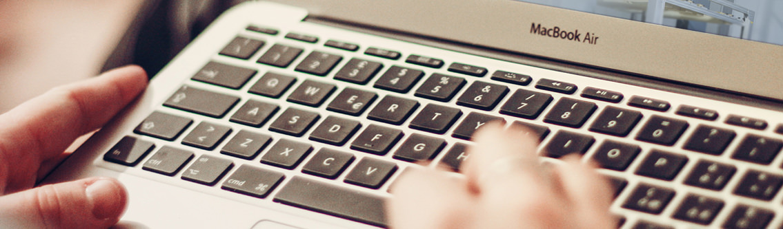Two hands typing on a MacBook keyboard.